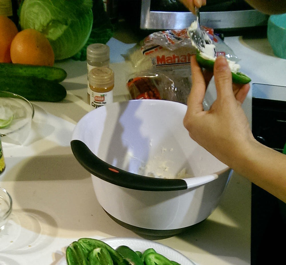 Jalapeno halves filled with cream cheese, mixing bowl, spoon